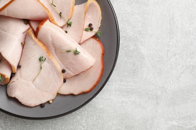 Photo of Delicious cut ham with thyme and peppercorns on light grey table, top view. Space for text