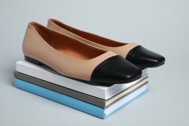 Photo of Stack of books with pair of new stylish square toe ballet flats on light grey background