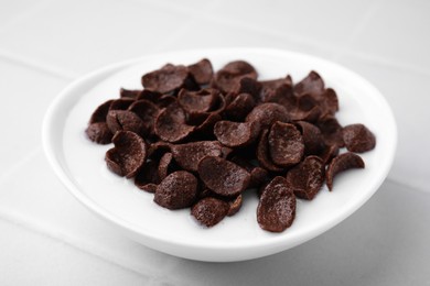 Photo of Breakfast cereal. Chocolate corn flakes and milk in bowl on white tiled table, closeup