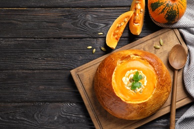 Photo of Flat lay composition with pumpkin soup served in bread and space for text on wooden background