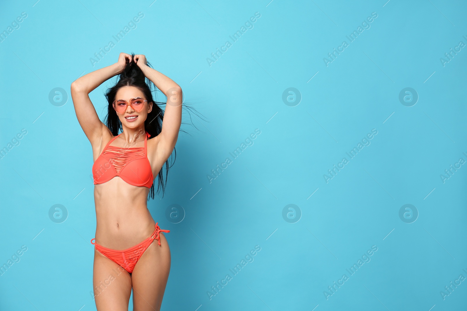 Photo of Beautiful young woman in stylish bikini with sunglasses on light blue background. Space for text