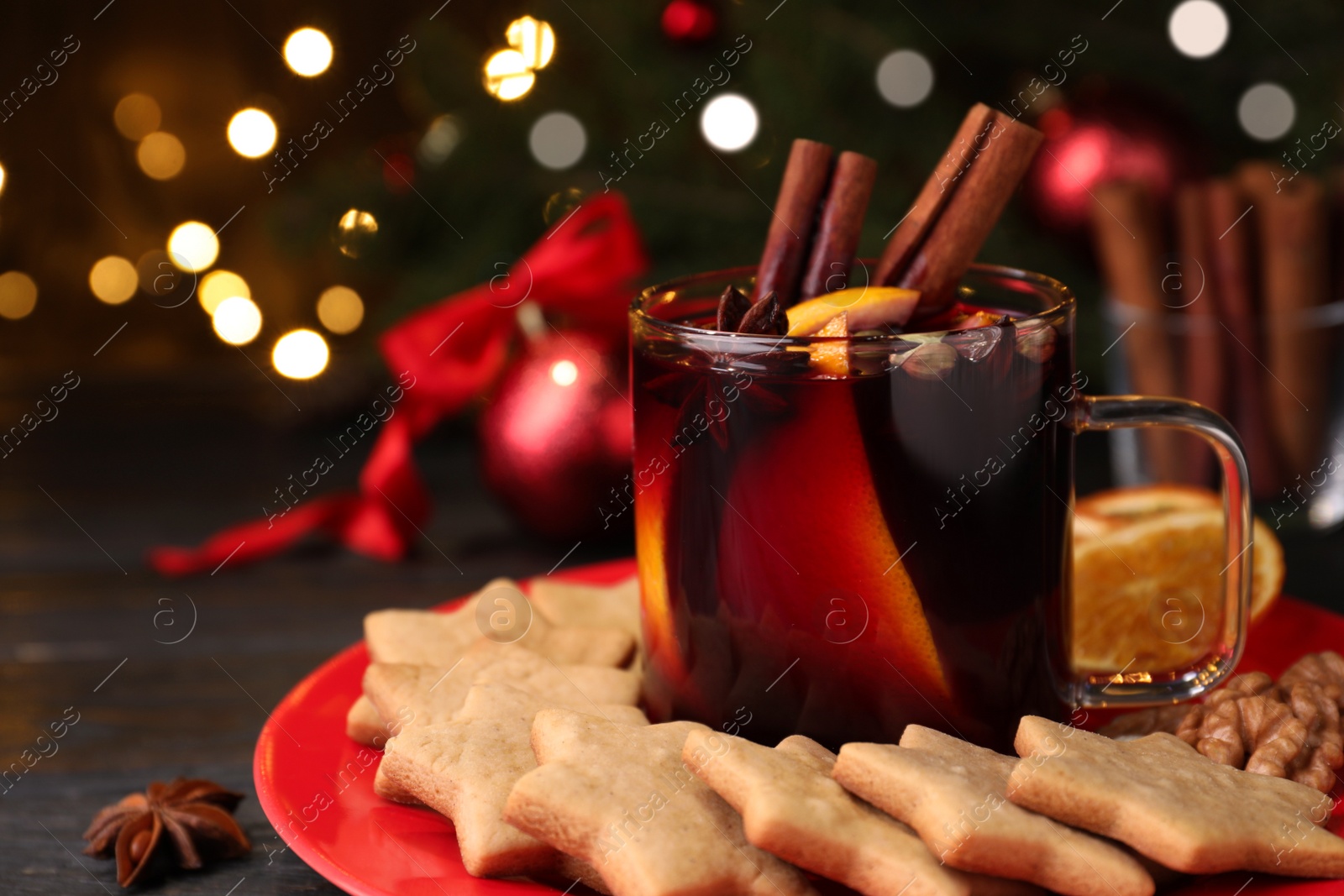 Photo of Aromatic mulled wine and cookies on wooden table, closeup