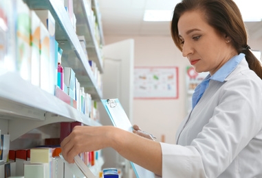 Image of Professional pharmacist near shelves with merchandise in modern drugstore