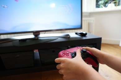 Photo of Child playing video games with controller at home, closeup