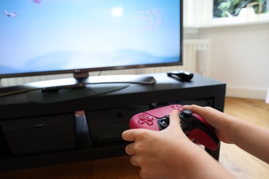 Child playing video games with controller at home, closeup