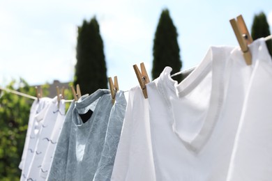 Photo of Washing line with clean clothes outdoors, closeup. Drying laundry outside