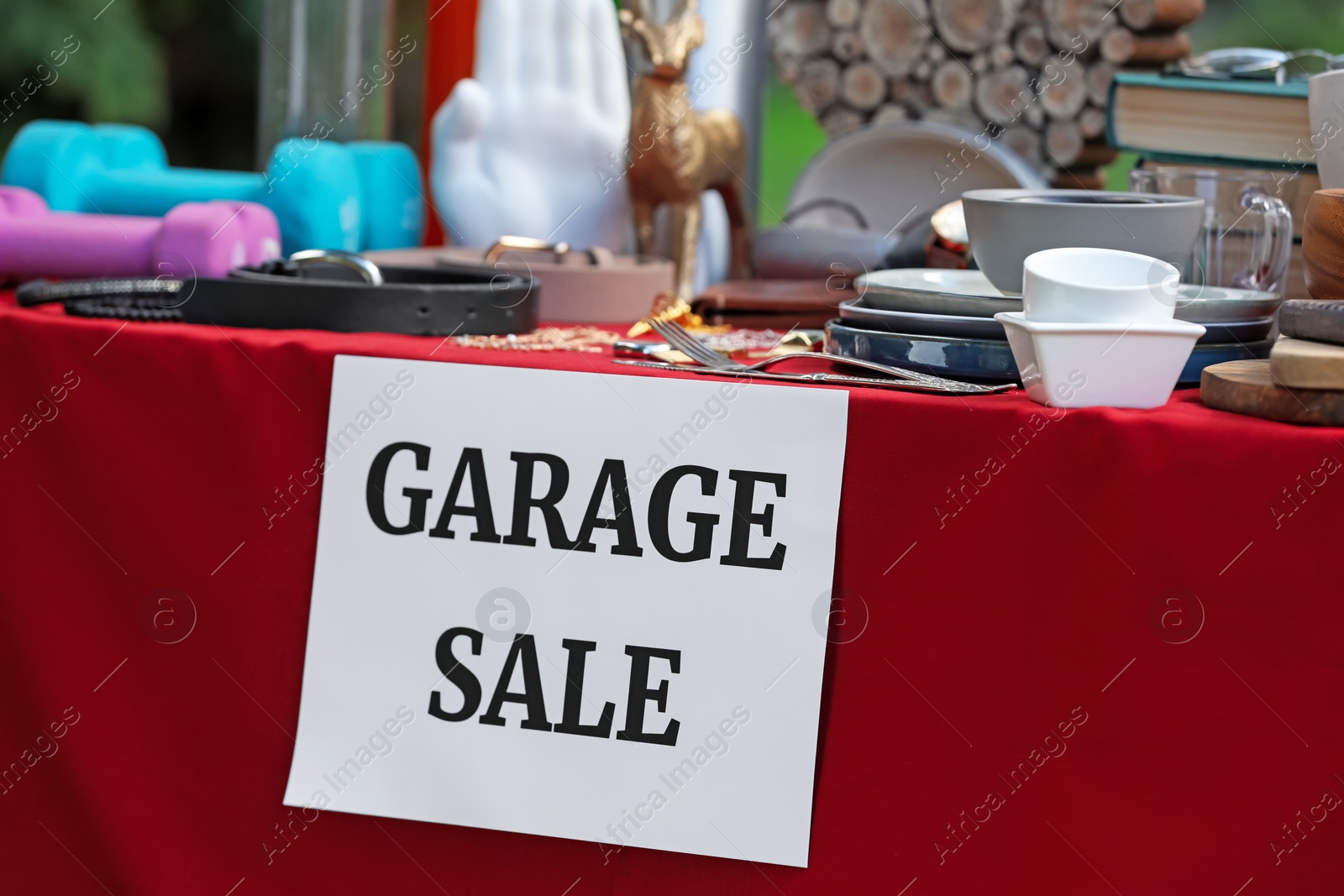 Photo of Paper with sign Garage sale and many different items on red tablecloth