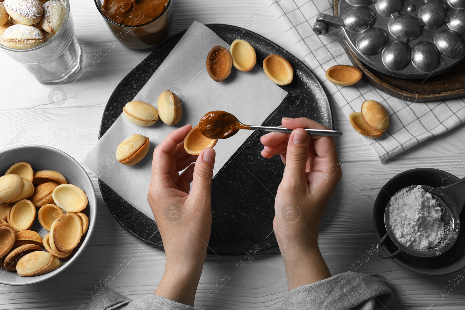 Photo of Woman making delicious walnut shaped cookies at white wooden table, top view