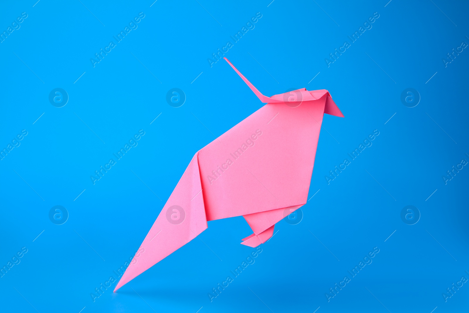 Photo of Origami art. Handmade pink paper parrot on light blue background