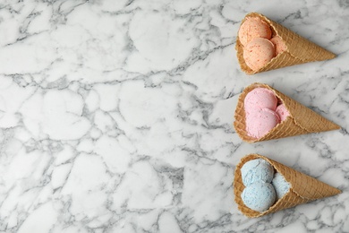 Flat lay composition with delicious ice creams in waffle cones on marble table, space for text