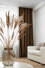 Fluffy reed plumes on white table in living room interior