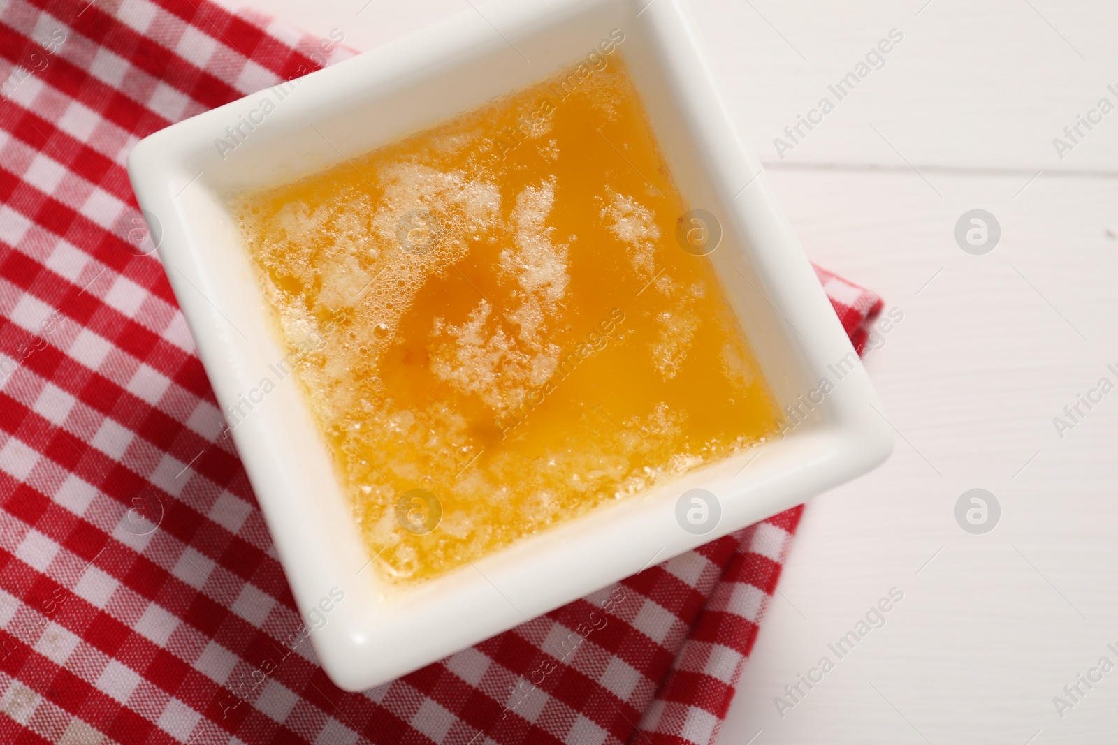 Photo of Melted butter in bowl on white wooden table, top view