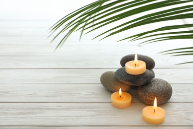 Composition with spa stones and candles on white wooden background. Space for text