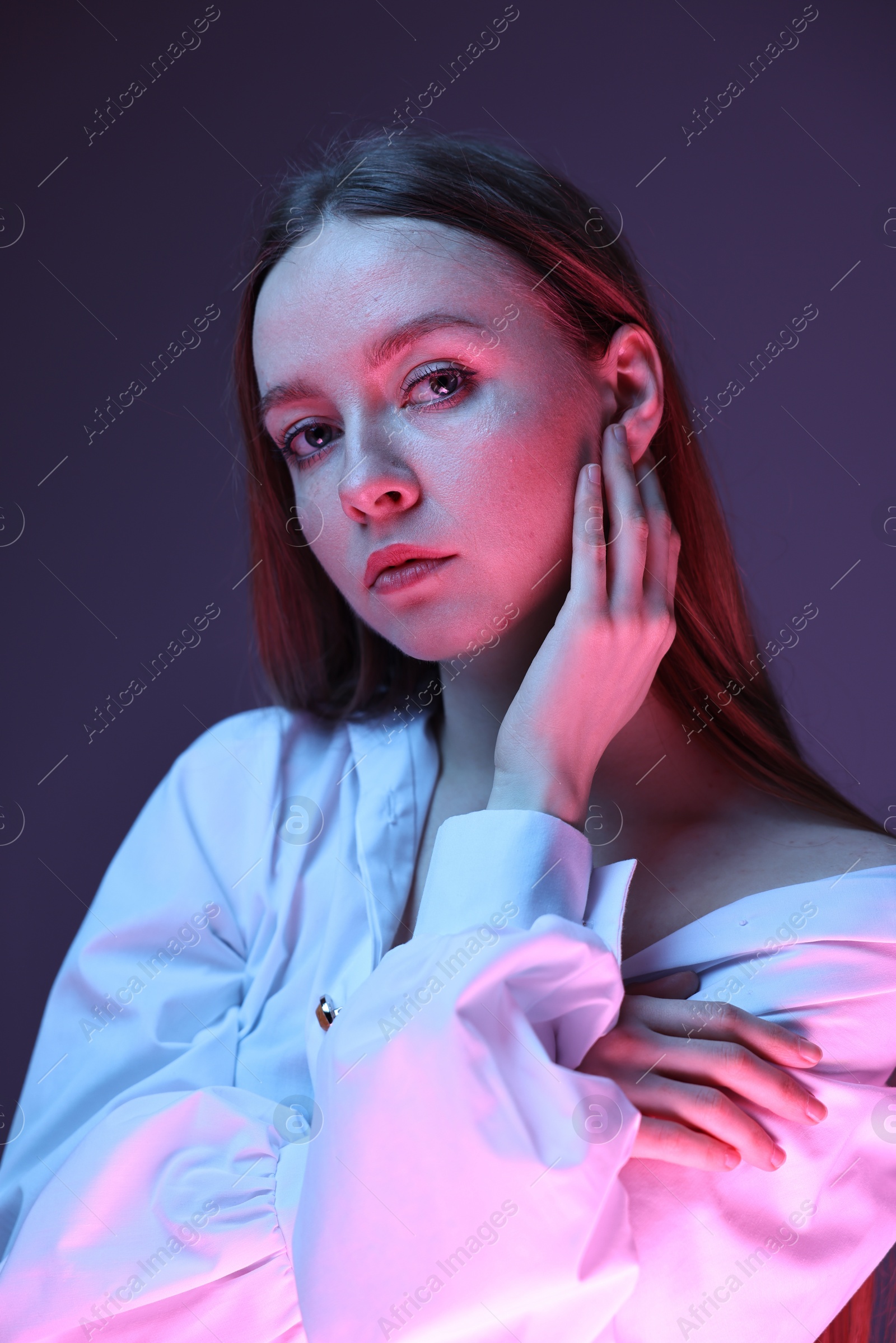 Photo of Fashionable portrait of beautiful young woman on purple background in neon lights