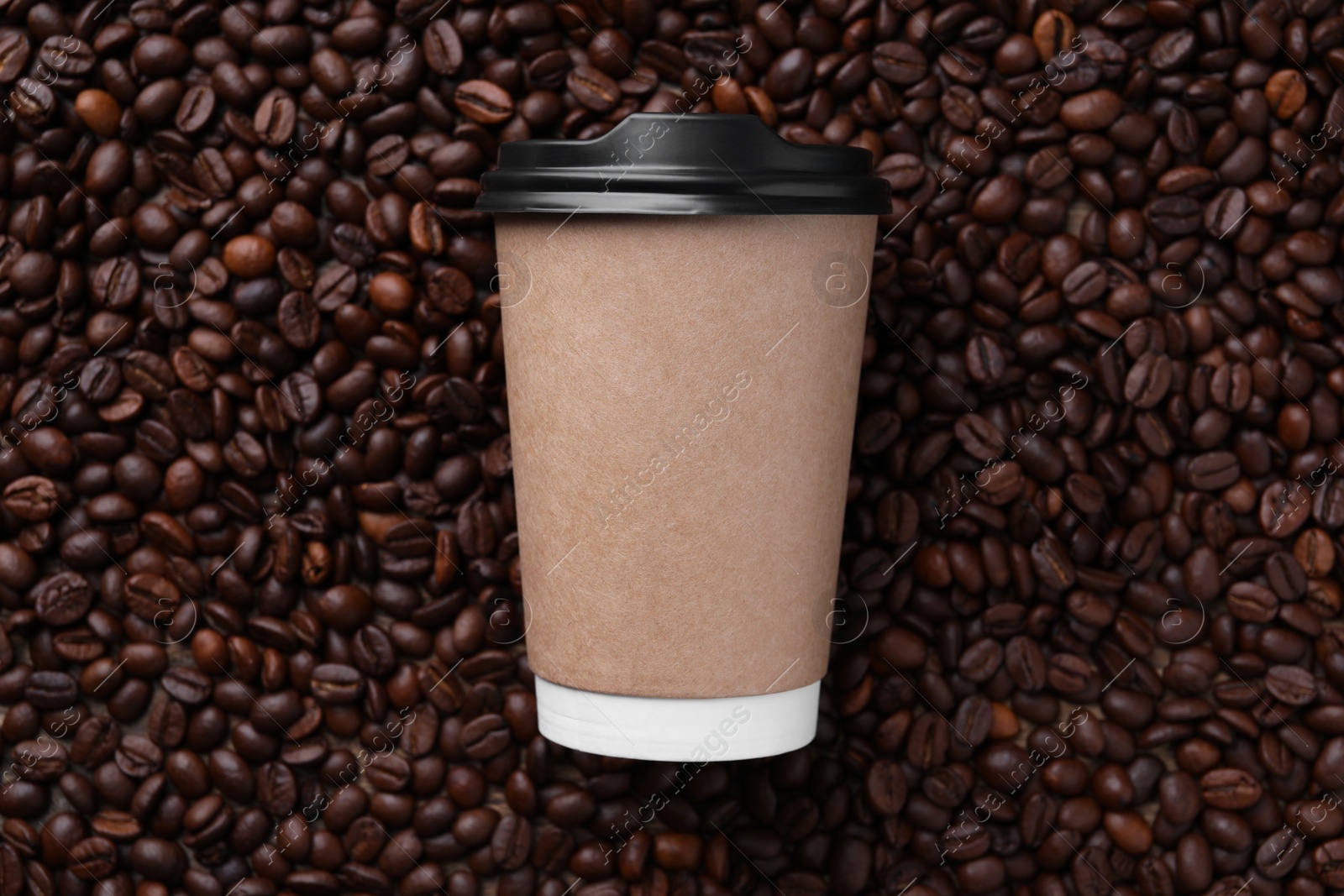 Photo of Coffee to go. Paper cup on roasted beans, top view