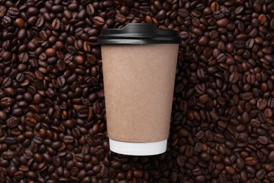 Photo of Coffee to go. Paper cup on roasted beans, top view