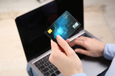 Photo of Online payment. Woman using credit card and laptop indoors, above view