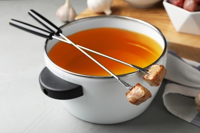 Fondue pot and forks with cooked meat on table