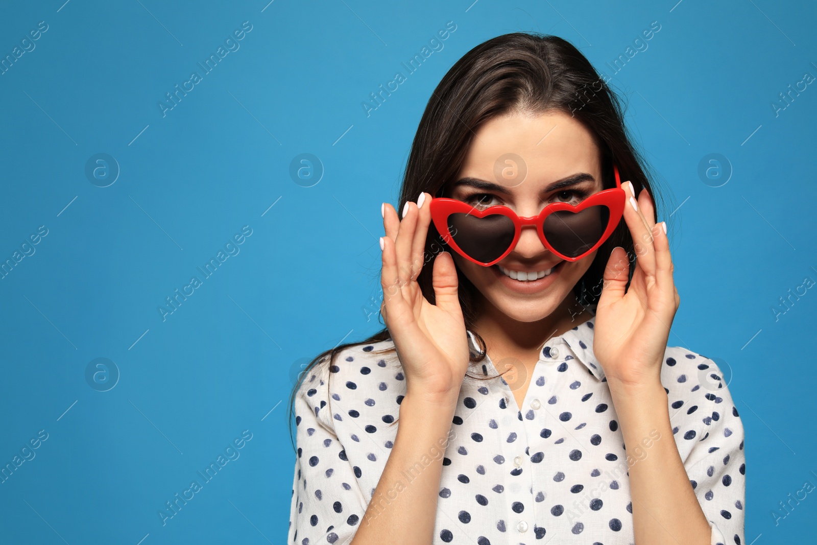 Photo of Portrait of beautiful young woman with heart shaped sunglasses on color background. Space for text