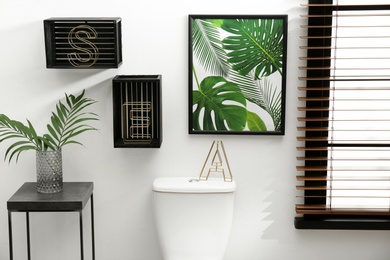 Photo of Table with vase and shelves near toilet bowl in restroom interior