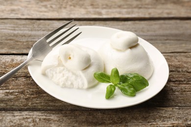 Delicious burrata cheese with basil on wooden table