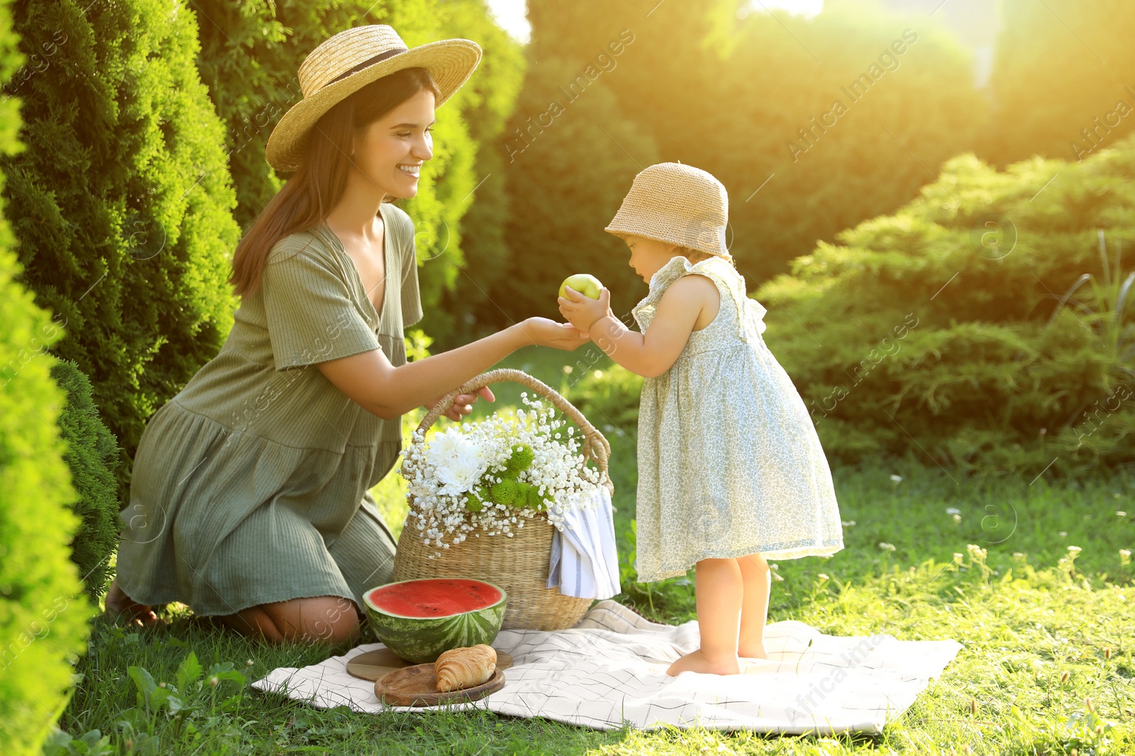 Photo of Mother with her baby daughter having picnic in garden on sunny day