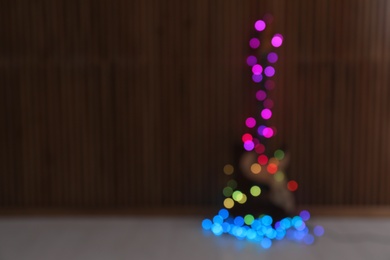 Blurred view of electric guitar with Christmas lights on floor. Space for text