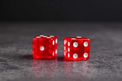 Two red game dices on grey textured table