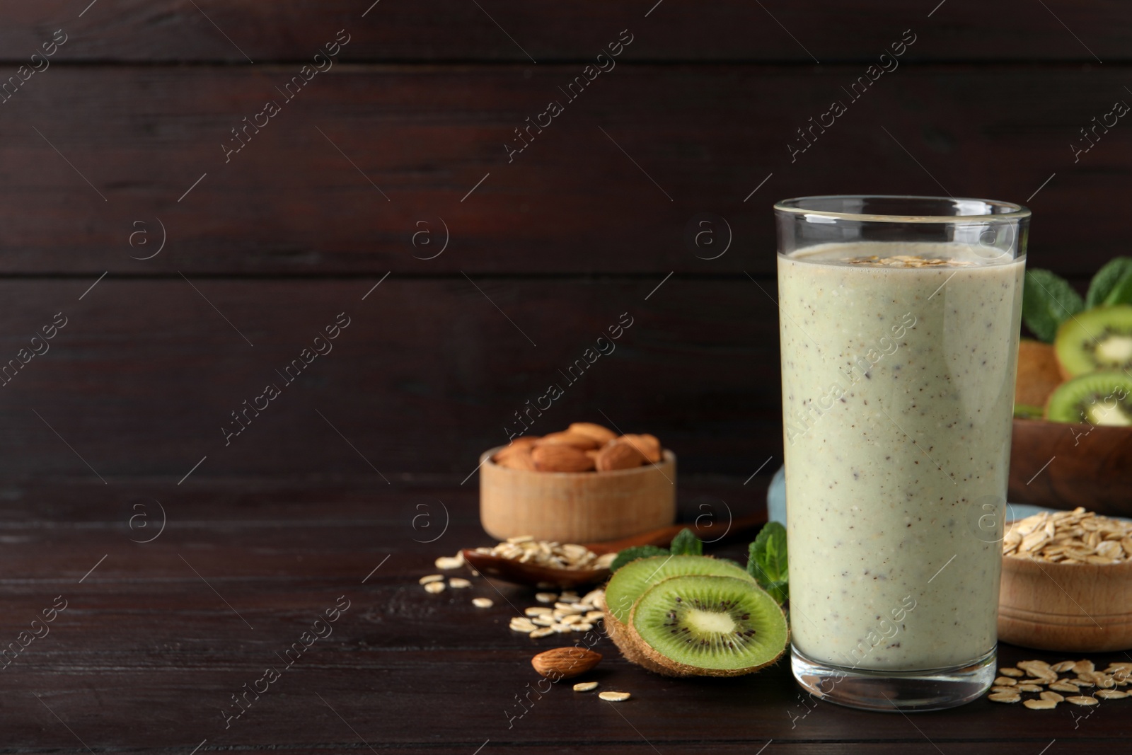 Photo of Glass of tasty kiwi smoothie with oatmeal on wooden table, space for text