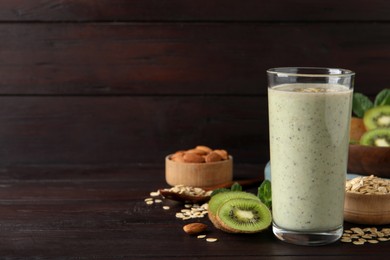 Photo of Glass of tasty kiwi smoothie with oatmeal on wooden table, space for text