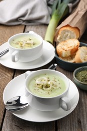 Photo of Delicious cream soup with leek and spices served on wooden table
