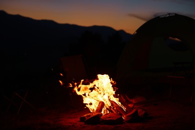 Photo of Beautiful bonfire near camping tent outdoors in evening