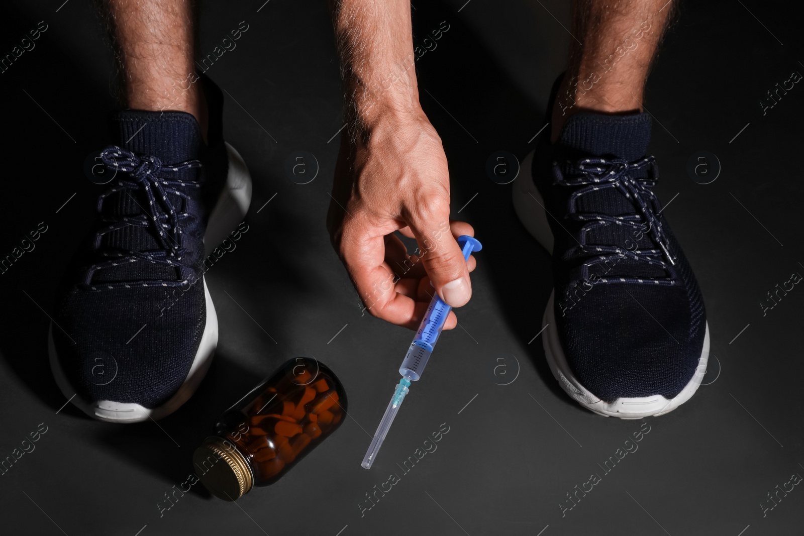 Photo of Man taking syringe from black floor, closeup. Doping concept