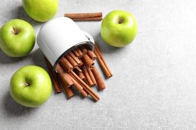 Photo of Fresh apples and mug with cinnamon sticks on table, top view