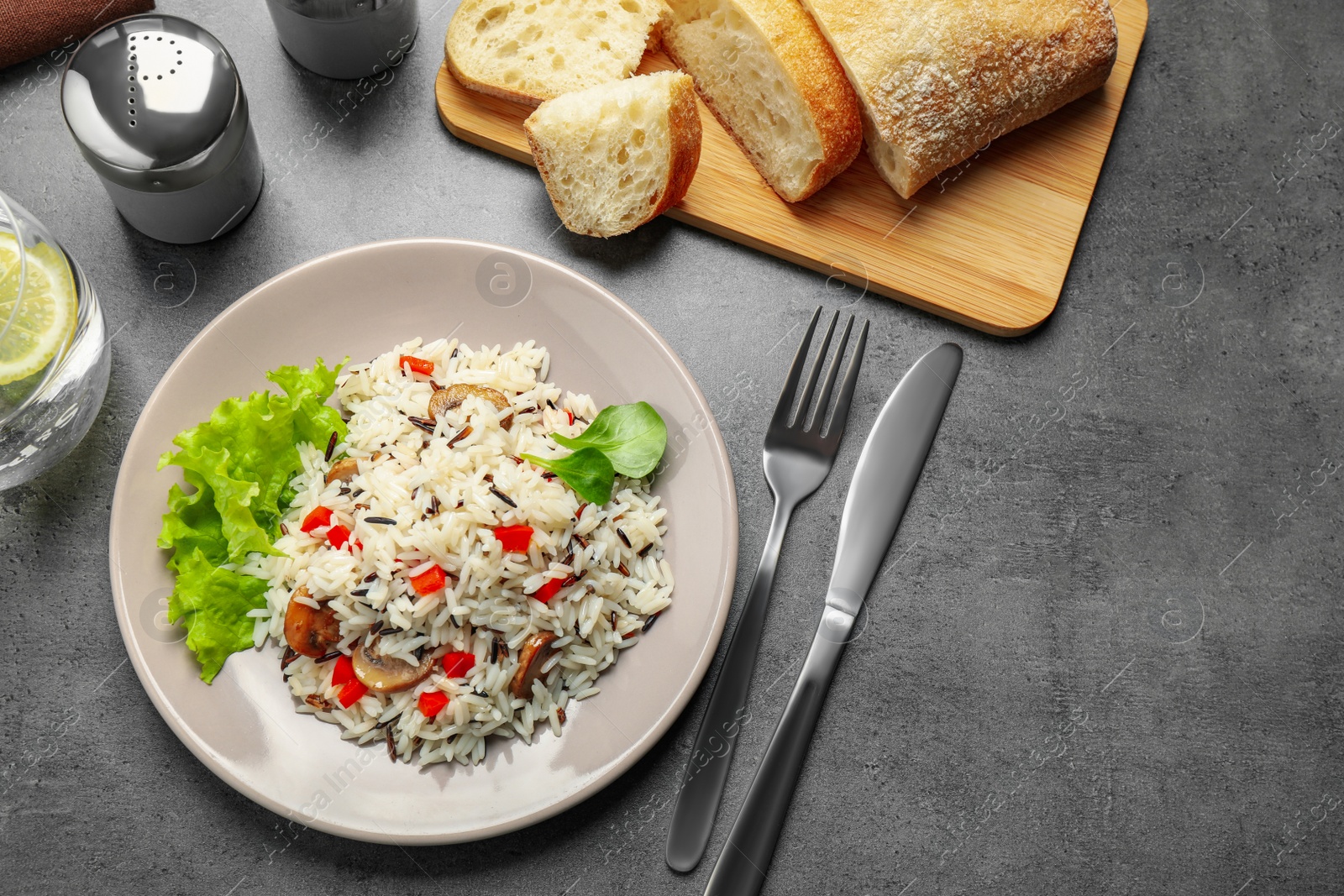 Photo of Delicious rice pilaf with mushrooms served on grey table, flat lay