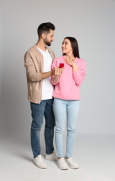 Photo of Man with engagement ring making marriage proposal to girlfriend on light grey background
