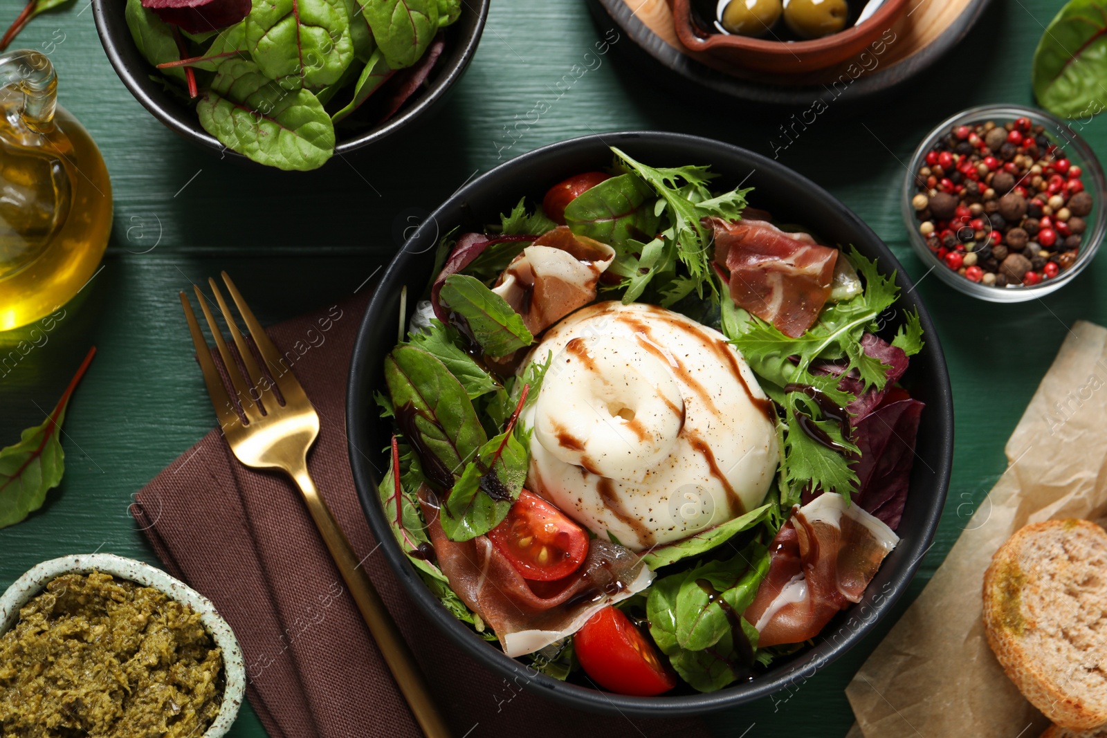 Photo of Delicious burrata salad served on green wooden table, flat lay