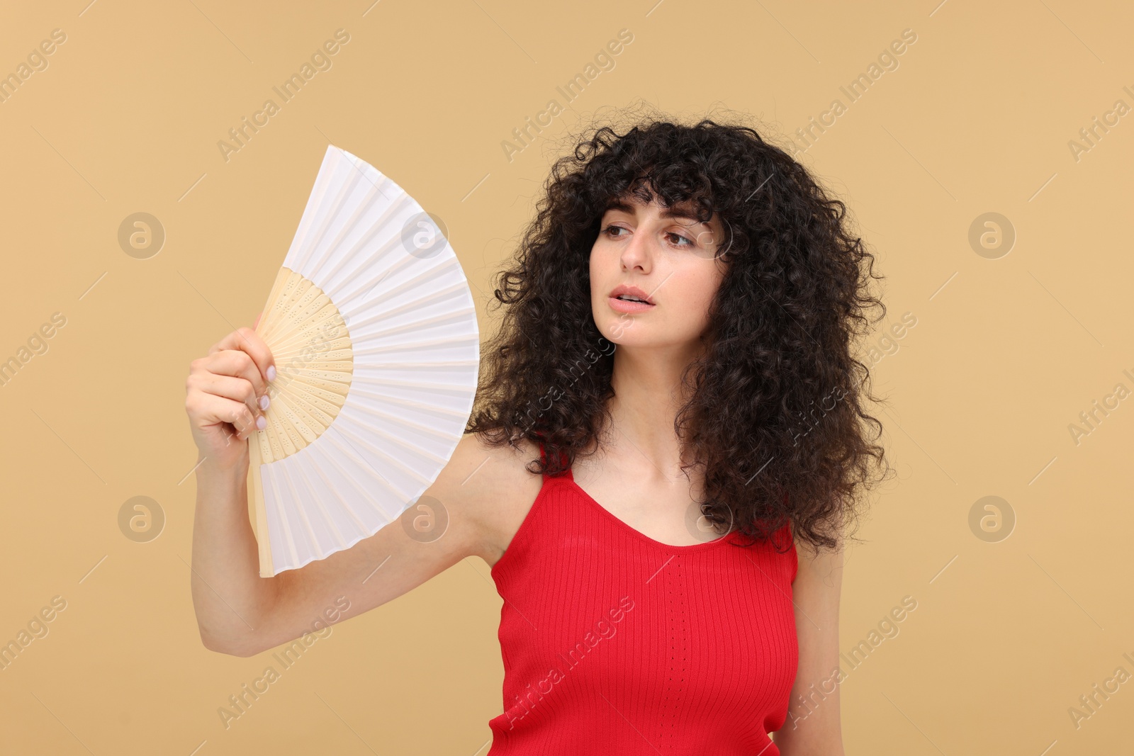 Photo of Woman with hand fan suffering from heat on beige background