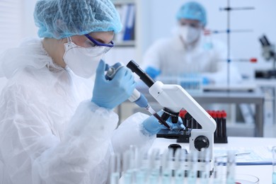 Photo of Scientist dripping sample onto glass slide while working with microscope in laboratory