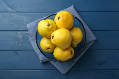 Tasty ripe quinces in bowl on blue wooden table, top view