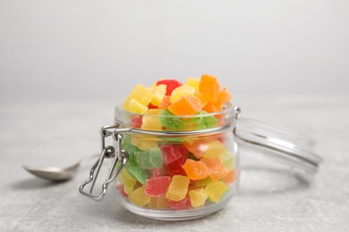 Mix of delicious candied fruits in jar on light grey table