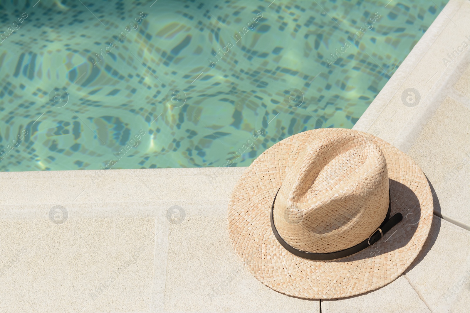 Photo of Stylish hat near outdoor swimming pool on sunny day, space for text. Beach accessory