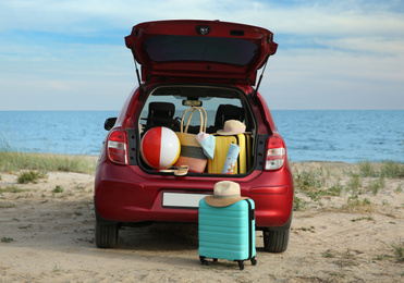 Photo of Red car with luggage on beach. Summer vacation trip