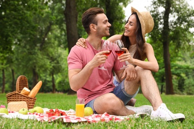 Happy young couple having picnic in park on summer day