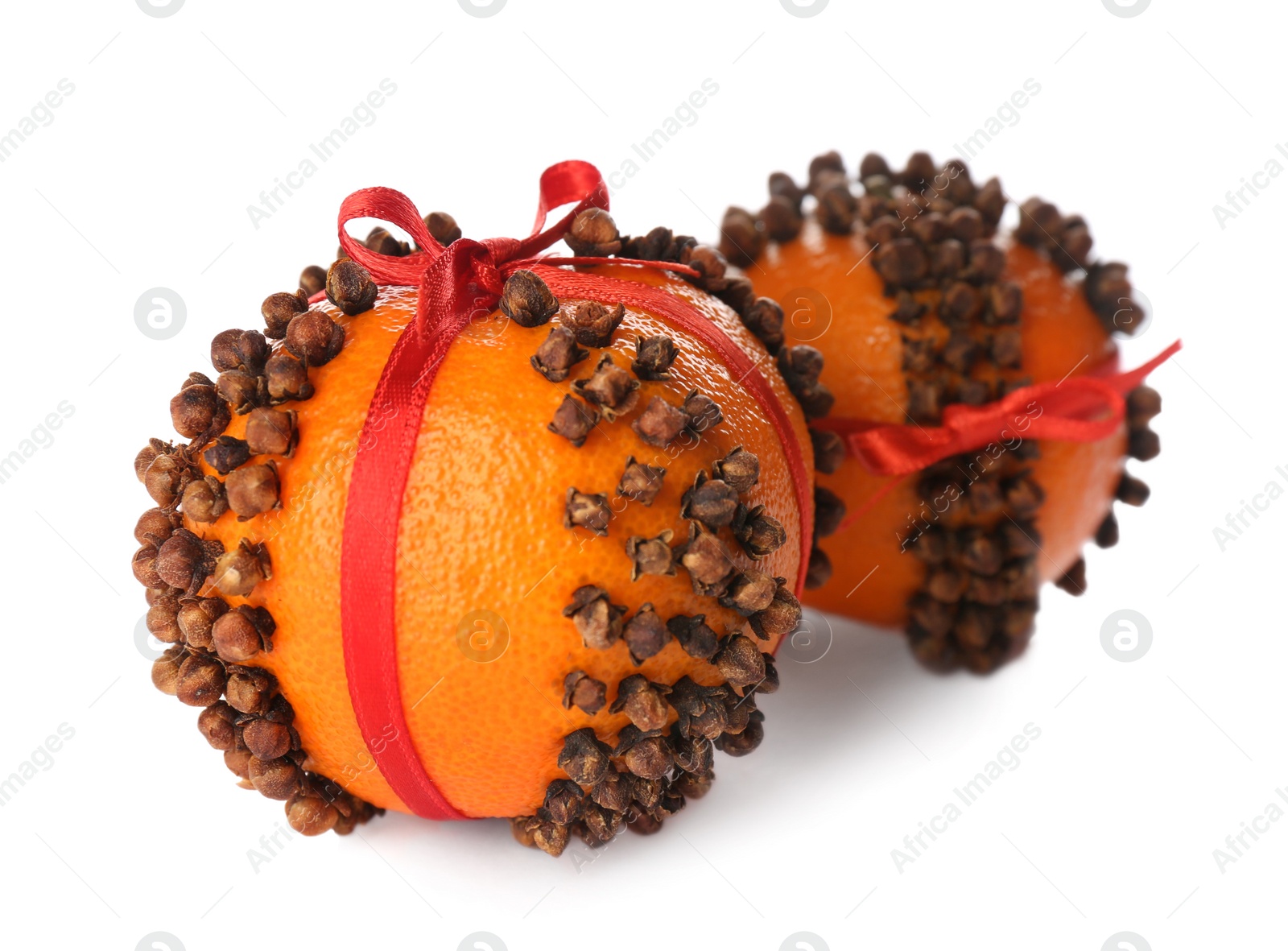 Photo of Pomander balls with red ribbons made of fresh tangerines and cloves on white background