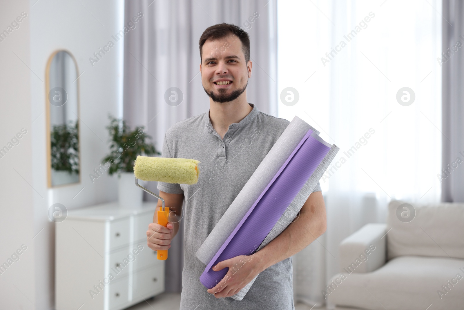 Photo of Man with wallpaper rolls and roller in room