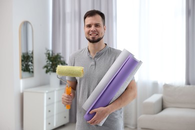 Man with wallpaper rolls and roller in room