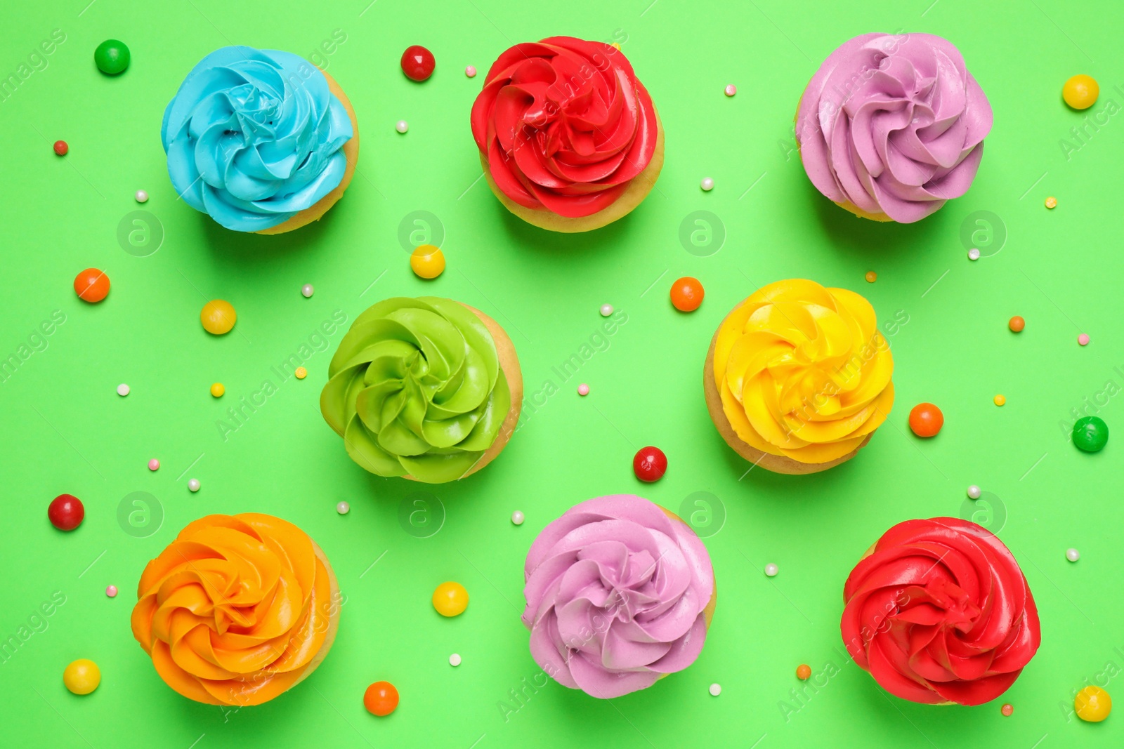 Photo of Colorful birthday cupcakes on green background, flat lay