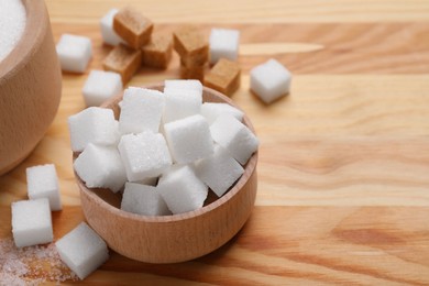 Photo of White sugar cubes in bowl on wooden table, closeup. Space for text