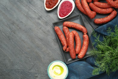 Photo of Tasty sausages and different sauces on black table, flat lay with space for text. Meat product